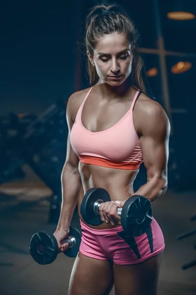 Sexy athletisches junges Mädchen trainiert Arme im Fitnessstudio — Stockfoto