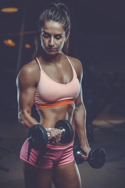 Sexy atlético joven entrenamiento brazos en el gimnasio — Foto de Stock