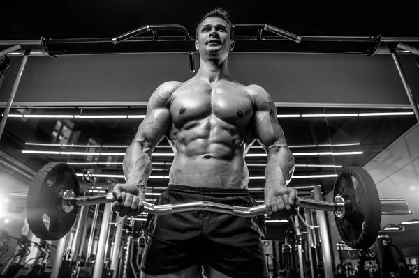 Bello modello giovane uomo formazione braccia in palestra — Foto Stock