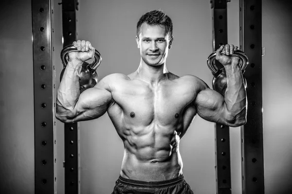 Bello giovane uomo che lavora in palestra kettlebel — Foto Stock