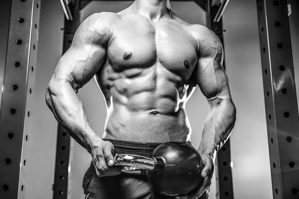 Handsome young man working out in gym kettlebel — Stock Photo, Image