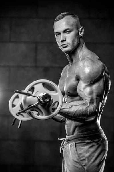 Guapo modelo joven entrenamiento brazos en el gimnasio —  Fotos de Stock