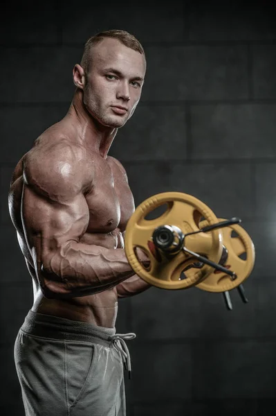 Guapo modelo joven entrenamiento brazos en el gimnasio —  Fotos de Stock