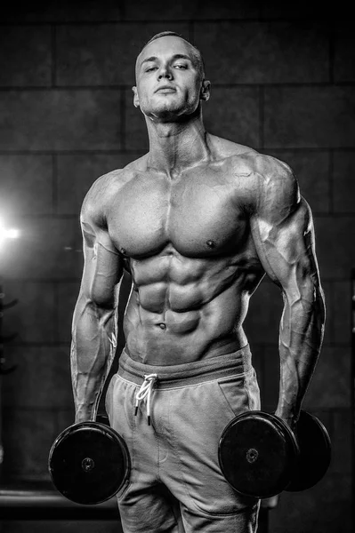 Brutal Caucasian bodybuilder training shoulders in gy — Stock Photo, Image