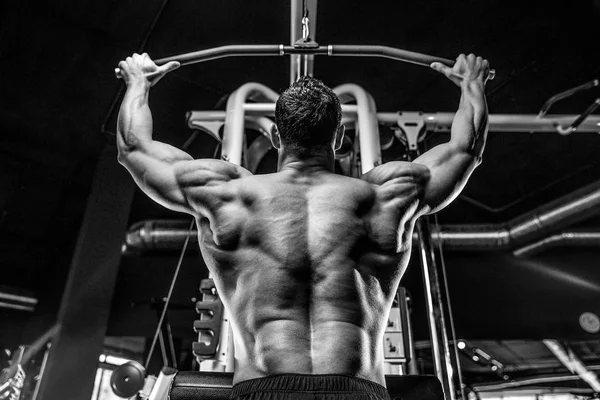 Guapo modelo joven entrenamiento de nuevo en el gimnasio —  Fotos de Stock