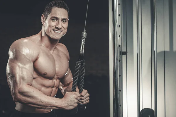 Handsome model young man training arms in gym