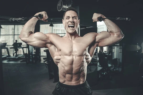 Handsome model young man training arms in gym