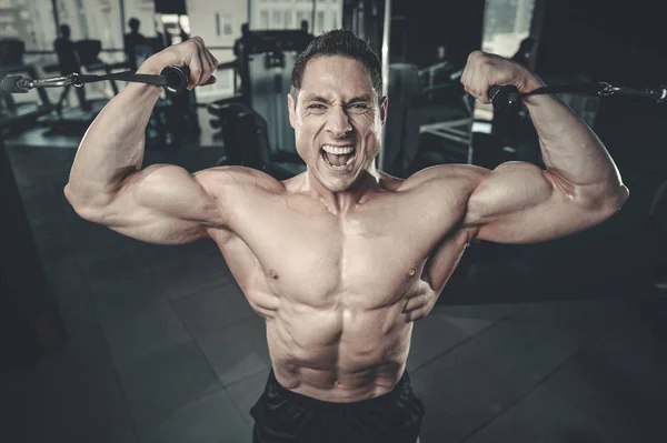 Gut aussehend modell junger mann training arms im fitnessstudio — Stockfoto