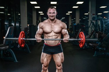 Yakışıklı model genç adam eğitim kollarında spor salonu