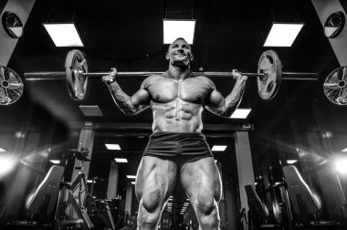 Yakışıklı model genç adam eğitim bacaklar içinde jimnastik salonu