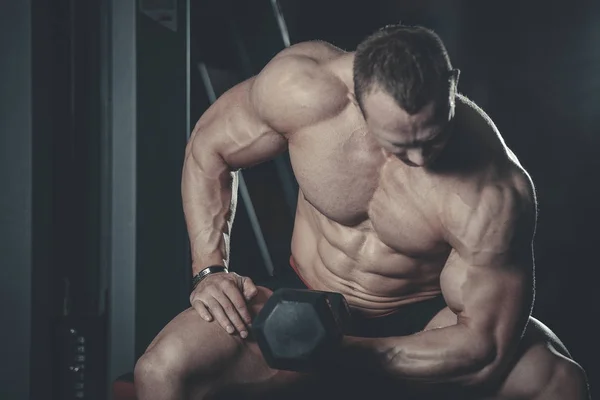 Guapo modelo joven entrenamiento brazos en el gimnasio —  Fotos de Stock