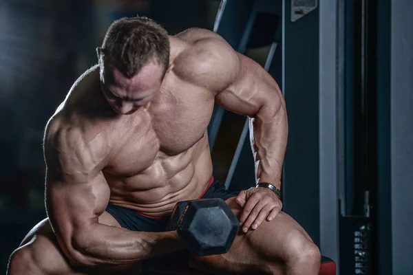 Guapo modelo joven entrenamiento brazos en el gimnasio —  Fotos de Stock