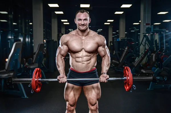 Guapo modelo joven entrenamiento brazos en el gimnasio — Foto de Stock