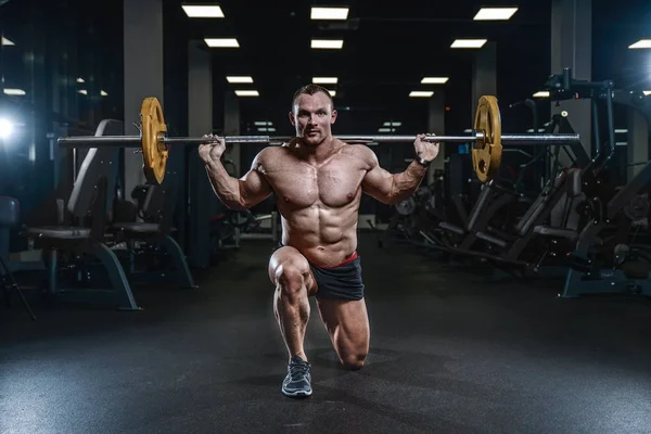 Guapo modelo joven entrenamiento piernas en el gimnasio — Foto de Stock