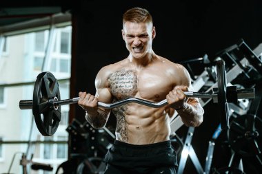 Yakışıklı model genç adam eğitim kollarında spor salonu