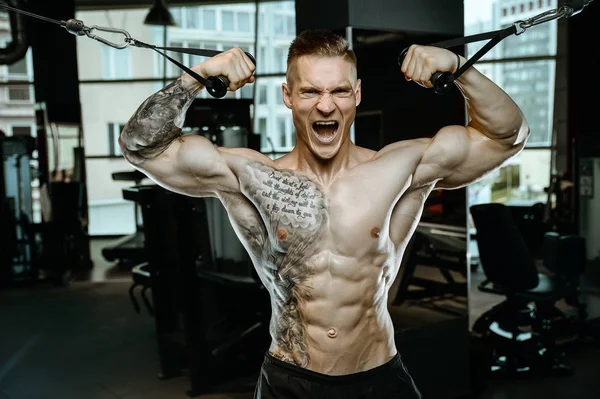 Gut aussehend modell junger mann training arms im fitnessstudio — Stockfoto