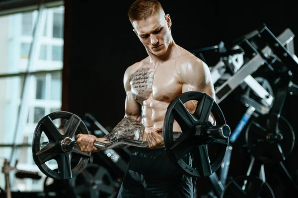 Yakışıklı model genç adam eğitim kollarında spor salonu