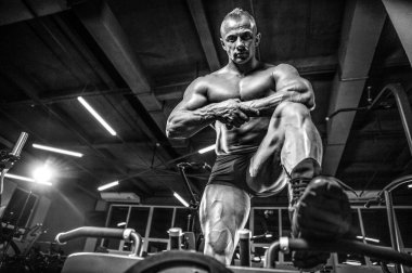 Yakışıklı model genç adam eğitim bacaklar içinde jimnastik salonu