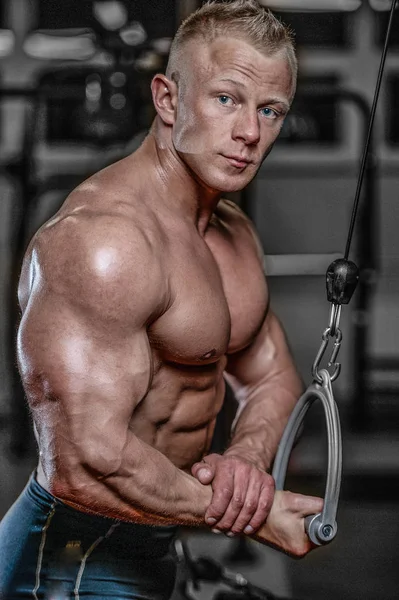 Guapo modelo joven entrenamiento brazos en el gimnasio —  Fotos de Stock