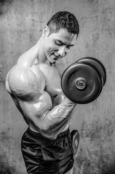 Guapo modelo joven entrenamiento brazos en el gimnasio —  Fotos de Stock