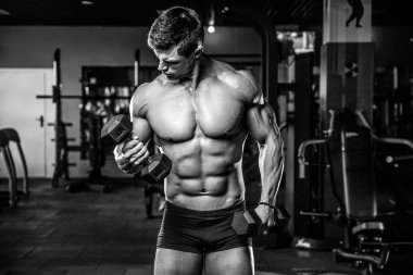 Yakışıklı model genç adam eğitim kollarında spor salonu