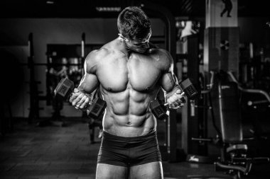 Yakışıklı model genç adam eğitim kollarında spor salonu