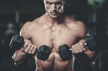 Yakışıklı model genç adam eğitim kollarında spor salonu