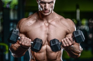 Yakışıklı model genç adam eğitim kollarında spor salonu