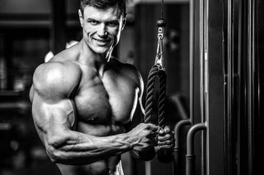 Yakışıklı model genç adam eğitim kollarında spor salonu