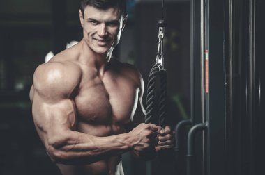 Yakışıklı model genç adam eğitim kollarında spor salonu