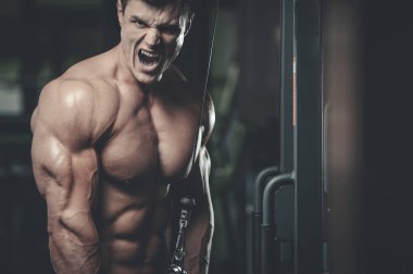 Yakışıklı model genç adam eğitim kollarında spor salonu