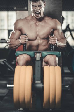 Yakışıklı model genç adam eğitim bacaklar içinde jimnastik salonu