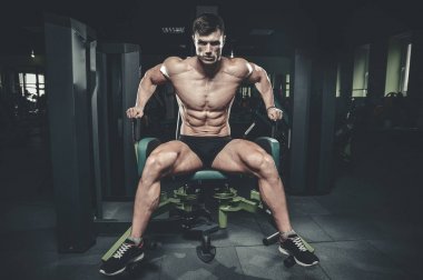 Yakışıklı model genç adam eğitim bacaklar içinde jimnastik salonu