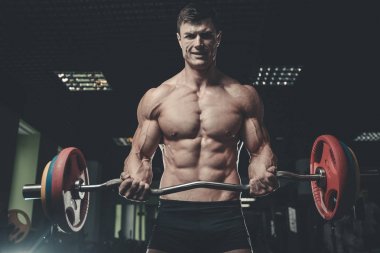 Yakışıklı model genç adam eğitim kollarında spor salonu