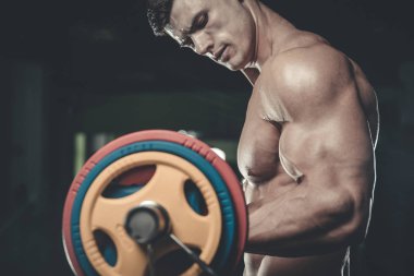 Yakışıklı model genç adam eğitim kollarında spor salonu