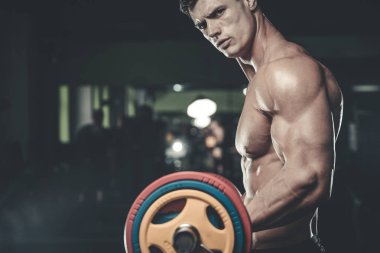 Yakışıklı model genç adam eğitim kollarında spor salonu