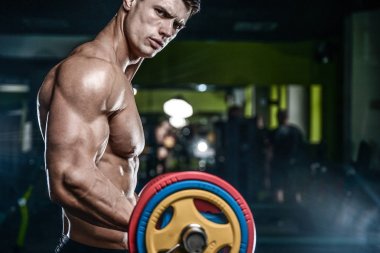 Yakışıklı model genç adam eğitim kollarında spor salonu