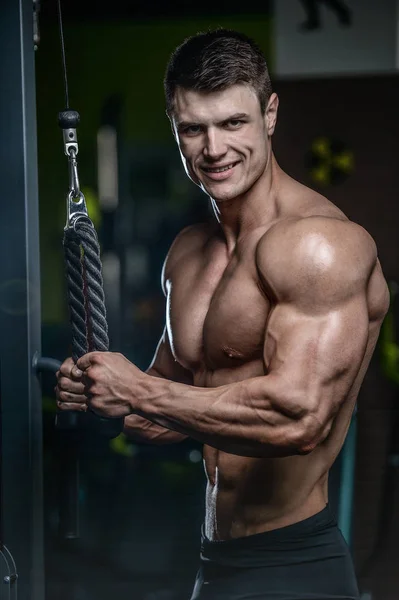 Guapo modelo joven entrenamiento brazos en el gimnasio —  Fotos de Stock