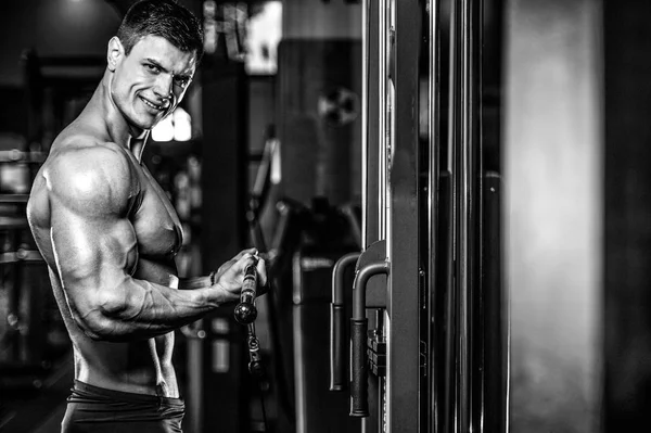 Yakışıklı model genç adam eğitim kollarında spor salonu