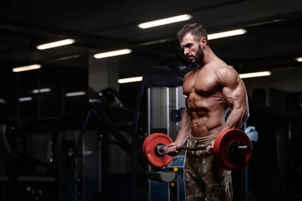 Seksi güçlü vücut geliştirmeci atletik erkek dum ile kasları kadar pompalama — Stok fotoğraf