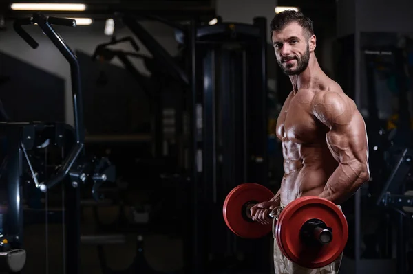 Σέξι bodybuilder ισχυρή άντληση τους μυς με dum αθλητική ανδρών — Φωτογραφία Αρχείου