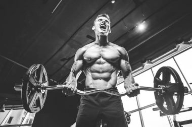 Yakışıklı model genç adam eğitim kollarında spor salonu