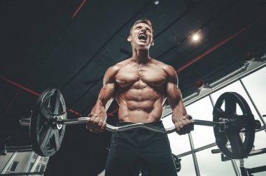 Yakışıklı model genç adam eğitim kollarında spor salonu