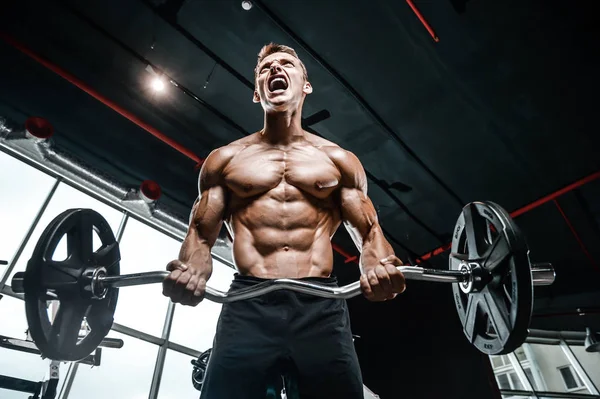 Bonito modelo jovem treinamento braços no ginásio — Fotografia de Stock