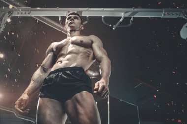 Güçlü vücut geliştirme sporcusu kas geliştirme konsepti geliştiren kaslı vücut geliştirici yakışıklı erkekler spor salonunda çıplak vücut egzersizleri yapıyor.
