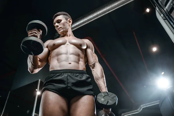 Guapo modelo joven entrenamiento brazos en el gimnasio —  Fotos de Stock