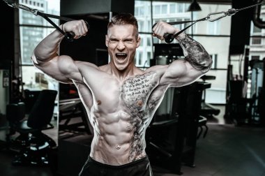 Yakışıklı model genç adam eğitim kollarında spor salonu