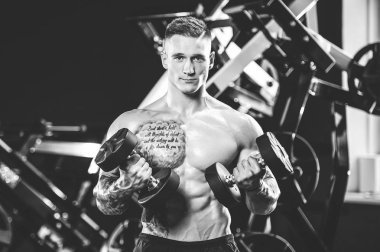 Yakışıklı model genç adam eğitim kollarında spor salonu