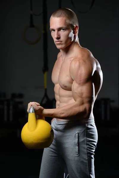 Bello giovane uomo che lavora in palestra kettlebel — Foto Stock