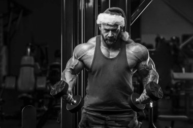 Spor salonunda Noel Baba kostümlü vücut geliştirici.